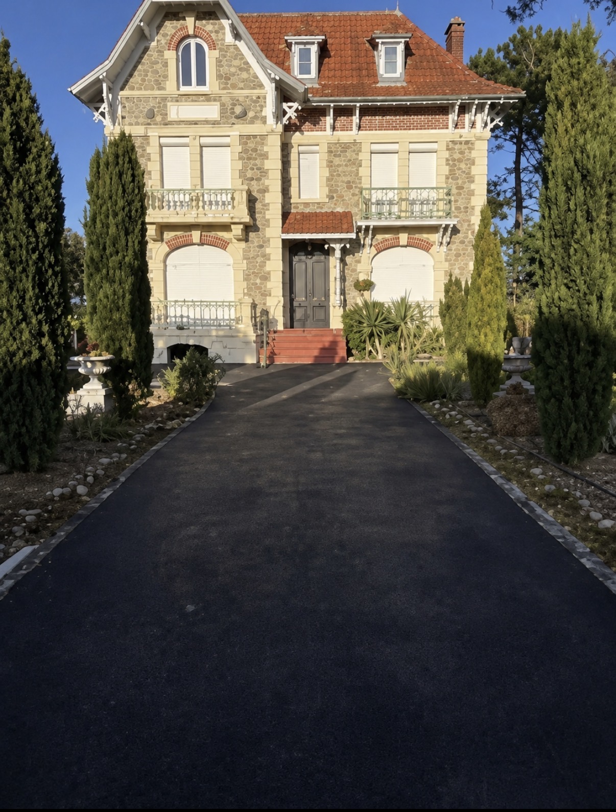 Allée en enrobé à chaud noir devant une maison de maître, bordures d'origine conservées et raccord net au pied du perron